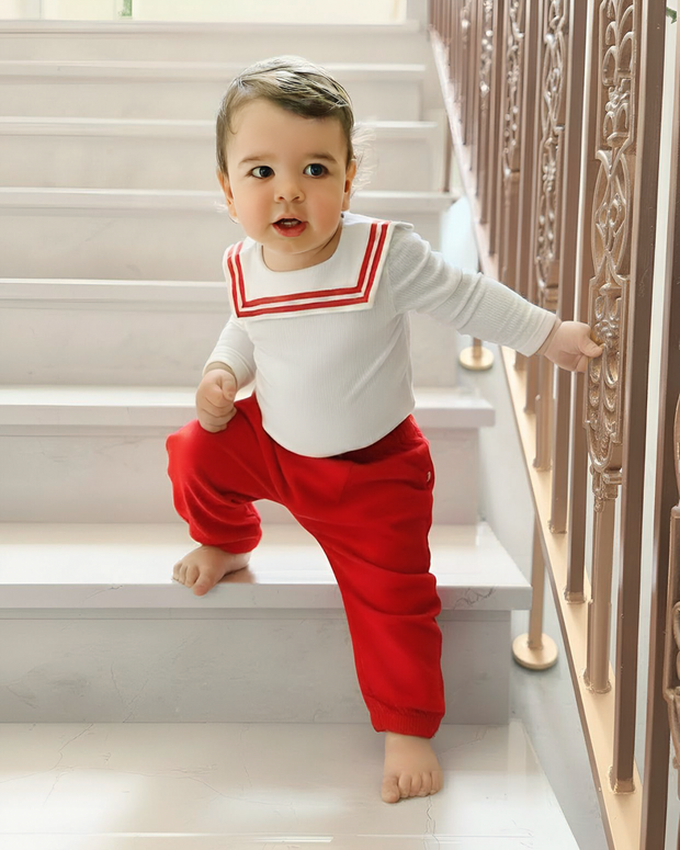 Top selling baby wearing white bamboo sailor-collar top and red pants by Atlas & Maya, showcasing winter wardrobe for infants.