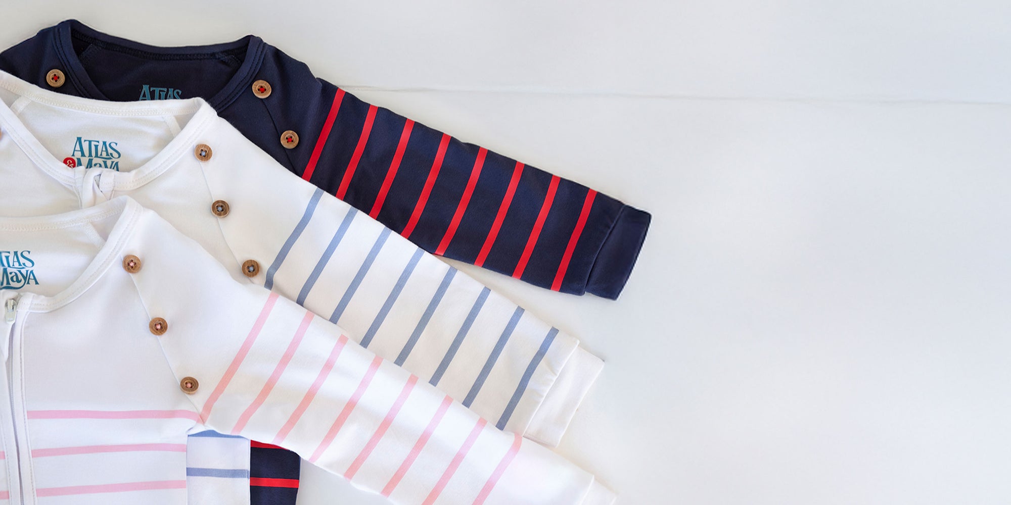 Striped long sleeve baby bamboo romper by Atlas & Maya in navy, blue, and pink laid flat on a neutral background.